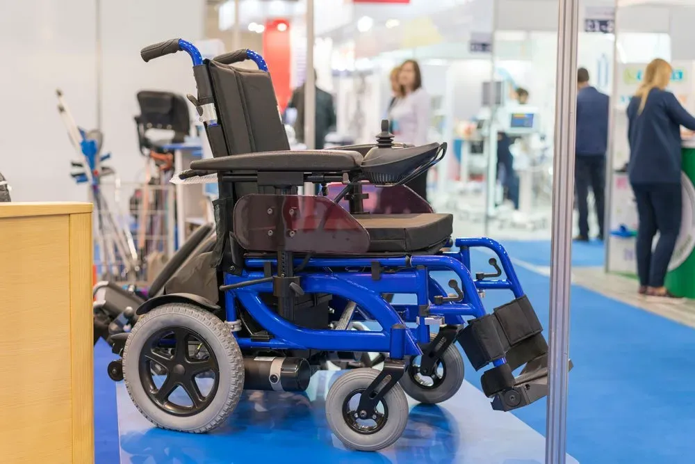 A black and blue electric wheelchair being displayed in a glass case