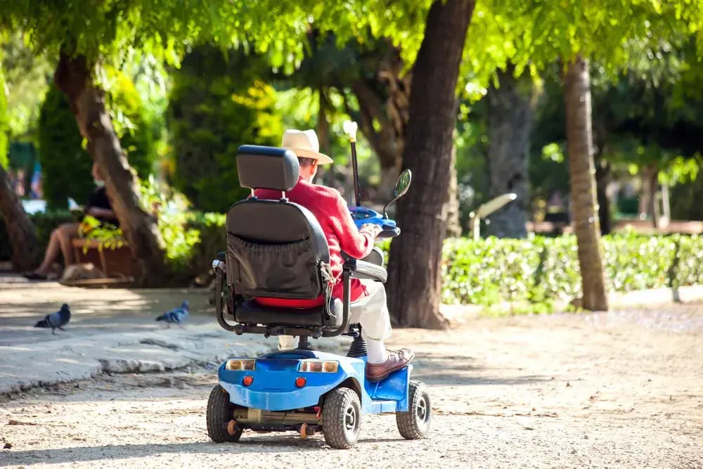 A man driving along a sandy road in a blue mobility scooter