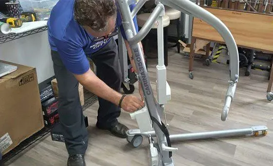 A man working on a patient lift device in a workshop