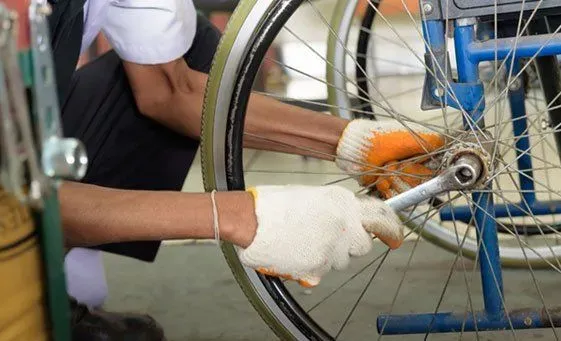 Gloved hands tightening a bolt on a wheelchair wheel