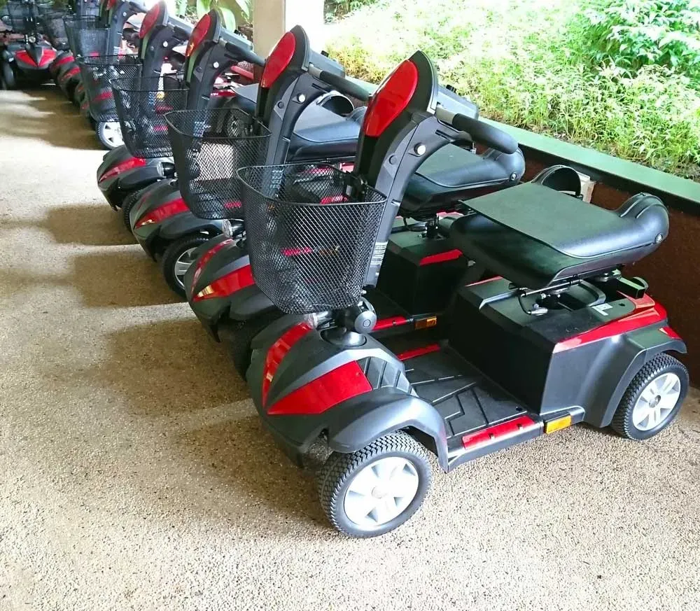 A row of black and red mobility scooters outside